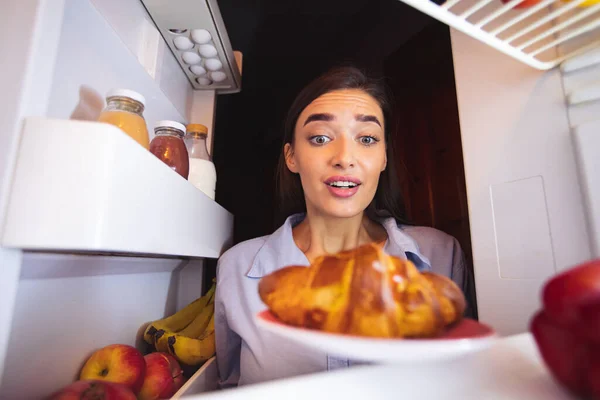Menina com fome olhando para croissant fresco na geladeira — Fotografia de Stock