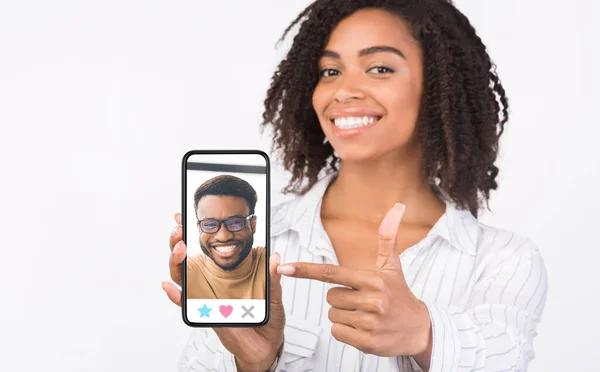 Schwarzes Mädchen zeigt Handy mit männlichem Profil auf dem Bildschirm — Stockfoto