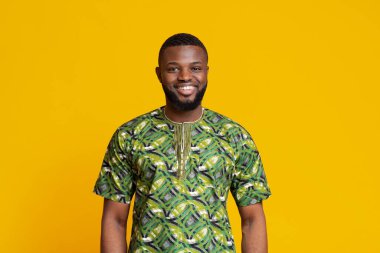 Yeşil otantik elbiseli Afrikalı adam sarı arka planda poz veriyor.