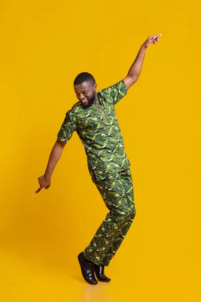 Безтурботний чорний хлопець в африканському костюмі танцює на жовтому фоні — стокове фото