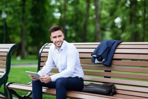 Confident CEO with tablet computer relaxing on bench in city park — Stock Photo, Image