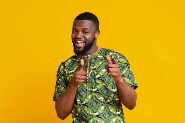 Playful african guy indicating to camera over yellow background — Stock Photo, Image