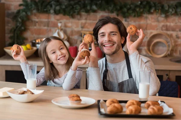 Domácí pekárna. Šťastný táta a malá dcera pózují s čerstvými pečenými muffiny — Stock fotografie
