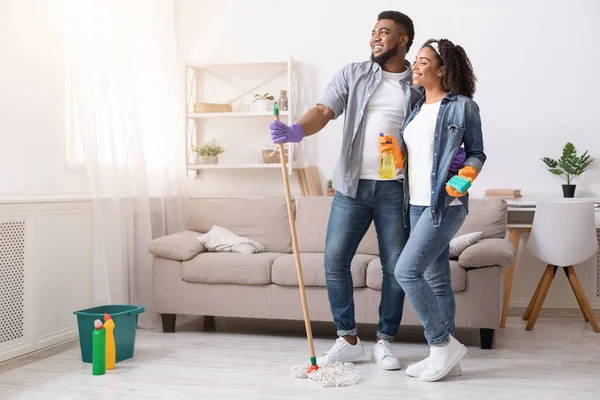 Glückliches schwarzes Paar steht im frisch gereinigten Wohnzimmer und schaut weg — Stockfoto