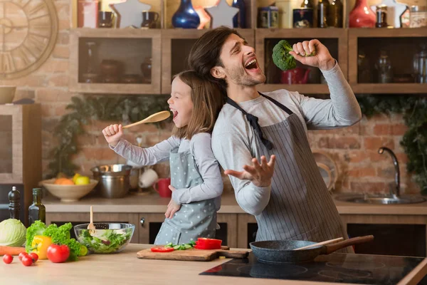 Mutfak eğlencesi. Neşeli baba ve küçük kızı birlikte yemek yaparken şarkı söylüyorlar. — Stok fotoğraf