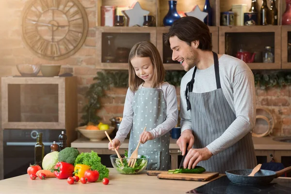 Családi főzés. Apa tanítja a kislányát, hogyan főzzön zöldséges salátát. — Stock Fotó