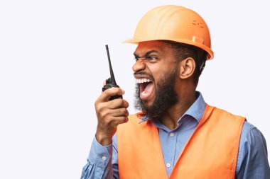 Angry Construction Foreman Worker Shouting In Two-Way Radio, Studio Shot clipart
