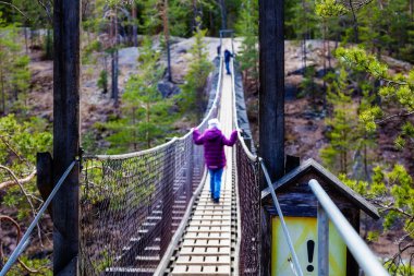 Kız ormanda bir asma köprü üzerinde yürüyor