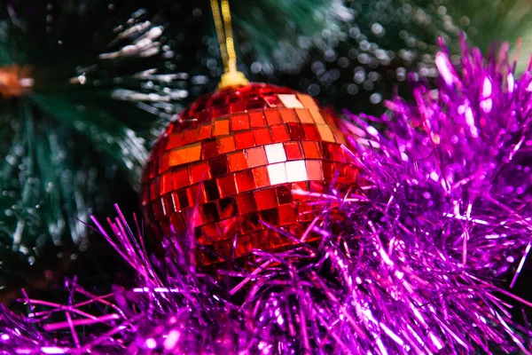 La guirnalda y la bola roja cuelgan de un árbol de Navidad sintético —  Fotos de Stock