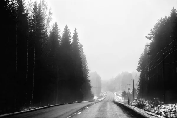 Uma estrada deserta está no nevoeiro em preto e branco — Fotografia de Stock