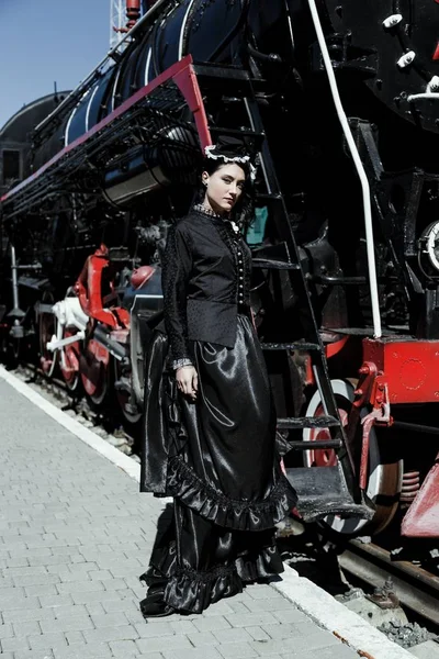 Mujer en vestido vintage cerca de locomotora de vapor — Foto de Stock