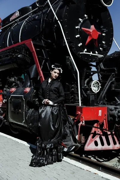 Mujer en vestido vintage cerca de locomotora de vapor — Foto de Stock