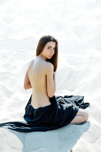 Piękna młoda kobieta siedzi na piasku — Zdjęcie stockowe