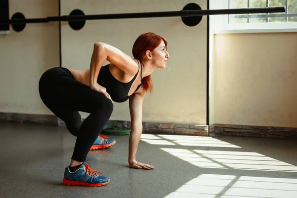 Mujer estirando sus piernas en el gimnasio — Foto de Stock