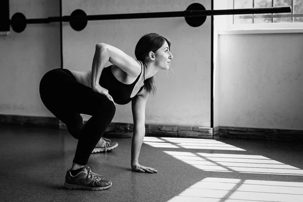 Mujer estirando sus piernas en el gimnasio — Foto de Stock