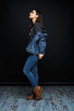 Karanlık studio arka planı poz denim giysiler içinde güzel genç esmer kadın