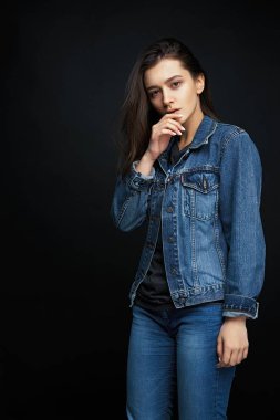 Karanlık studio arka planı poz denim giysiler içinde güzel genç esmer kadın