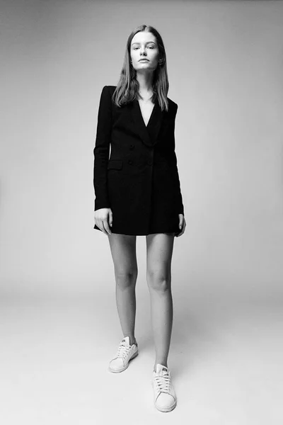 Gorgeous fashion model in black fashionable jacket posing against studio background