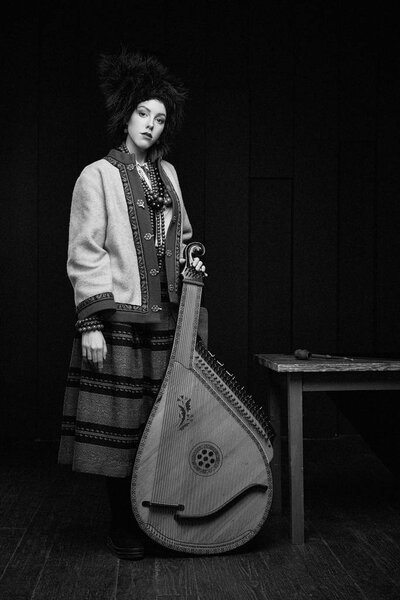 Gorgeouns young woman in ukrainian traditional costume with ukrainian musical instrument bandura 