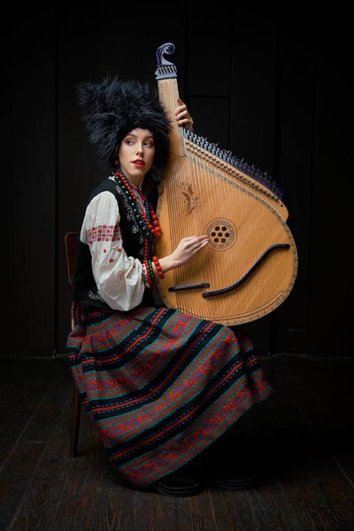 Gorgeouns young woman in ukrainian traditional costume with ukrainian musical instrument bandura 