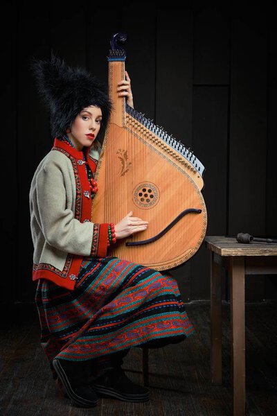 Gorgeouns young woman in ukrainian traditional costume with ukrainian musical instrument bandura 