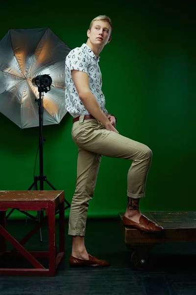 英俊的年轻人穿着时髦的衣服摆在绿色工作室背景 — 图库照片
