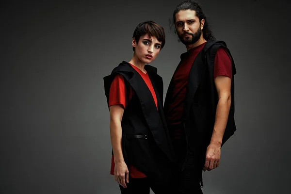 Young stylish couple posing against dark studio background