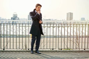 Şık yakışıklı genç adam sokakta Sigara