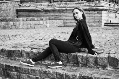 Siyah ve beyaz fotoğraf sokakta poz rahat kıyafetler içinde genç ve güzel kadın                 