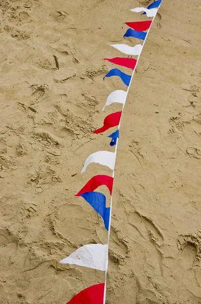 Drapeaux de bruants colorés sur la surface du sable — Photo