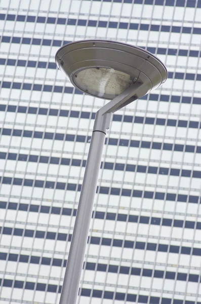 Um moderno poste de lâmpada de rua contra um edifício cinzento . — Fotografia de Stock