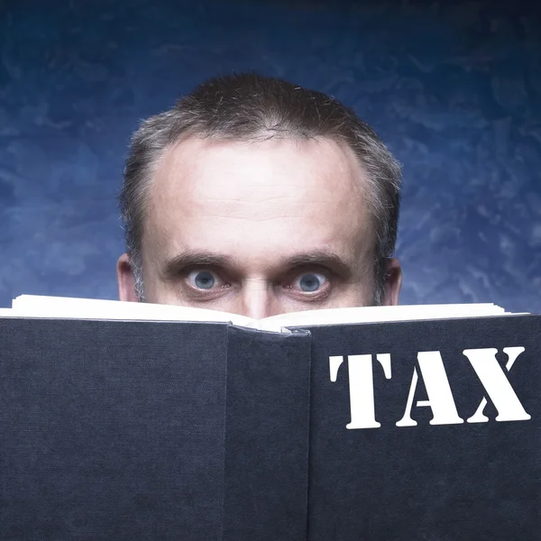 Зрелый человек сосредоточен и увлечен книгой о налогах — стоковое фото