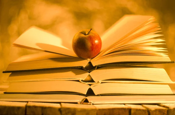 Bücher und Apfel auf goldenem Hintergrund — Stockfoto