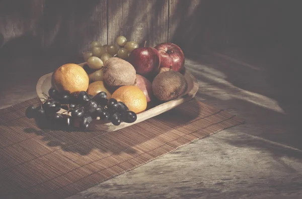 Sortiment frische gesunde Früchte in handgemachter Holzschale aus Ecuador auf Holzhintergrund mit Kopierraum. — Stockfoto