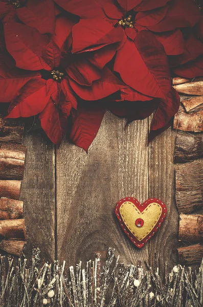 Frame arranged from poinsettia flowers, sticks, twigs, driftwood, coconut shell as a background. Handmade from felt heart. Craft. — Stock Photo, Image