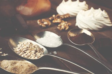 Kaşık şeker, kahve, yulaf ve beze, çikolata şekerleme, bal ve fındık gerçek kahverengi ahşap bir masa ile.