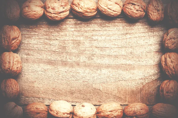 Simple frame arranged from walnuts on wooden background. — Stock Photo, Image