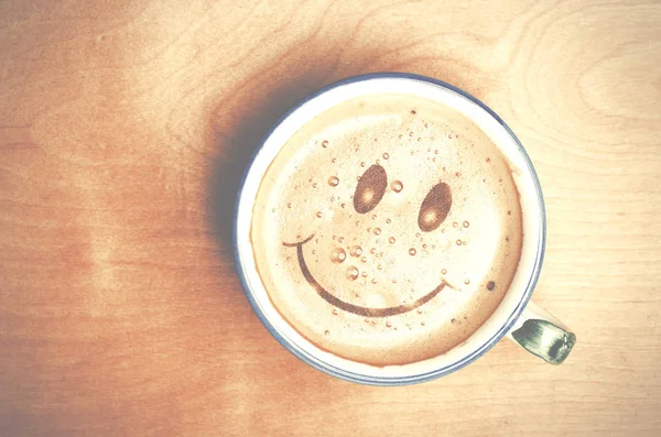 Forma de espuma de rosto sorriso na xícara de café Cappuccino na mesa de madeira — Fotografia de Stock