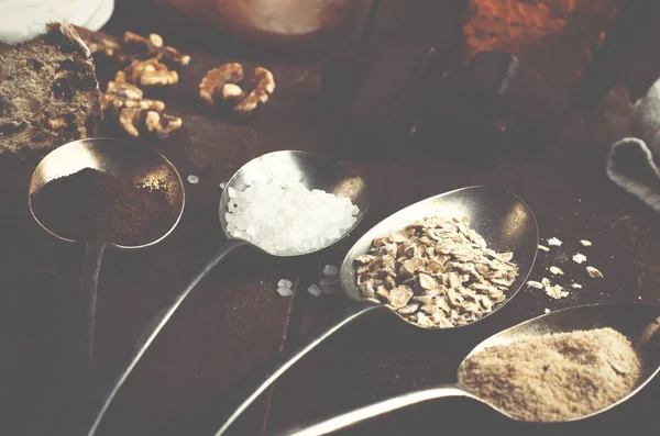 Cucharas con azúcar, café, avena y merengue, malvavisco de chocolate, miel y nueces en una mesa de madera marrón real . — Foto de Stock