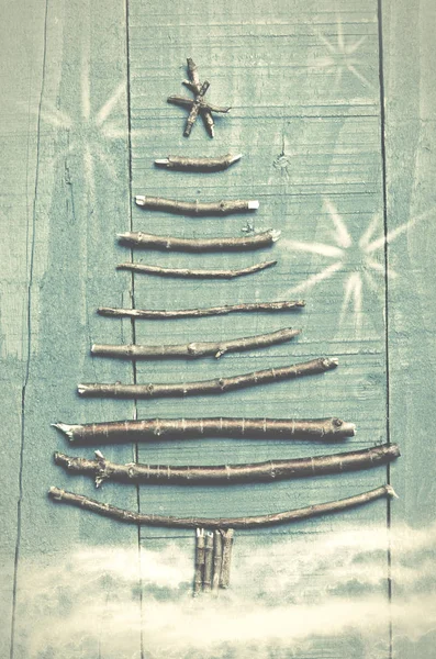 Albero di Natale realizzato con bastoncini asciutti su sfondo di legno blu. Immagine di fiocchi di neve e neve. Ornamento albero di Natale . — Foto Stock