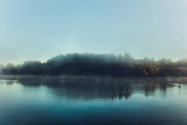 Туманный пейзаж и облака над водой — стоковое фото