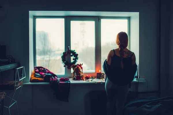 Κορίτσι στέκεται κοντά σε παράθυρο με Χριστουγεννιάτικη διακόσμηση — Φωτογραφία Αρχείου