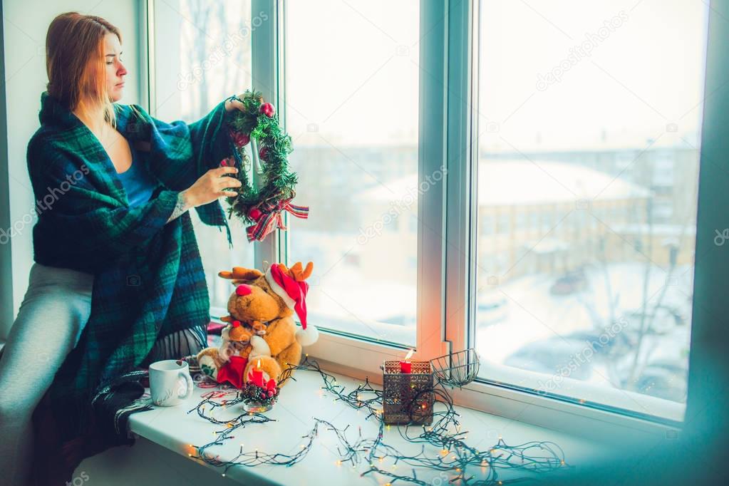 girl hanging wreath on window