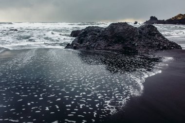 Siyah kum ve taş ile deniz kıyısı