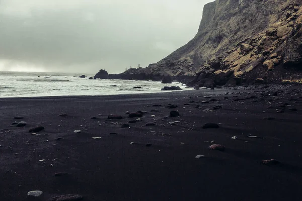 Kust met zwart zand en stenen — Stockfoto