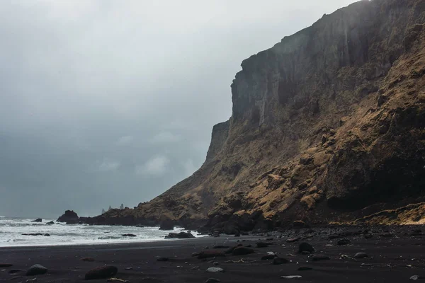 Mar com areia preta e pedras — Fotografia de Stock