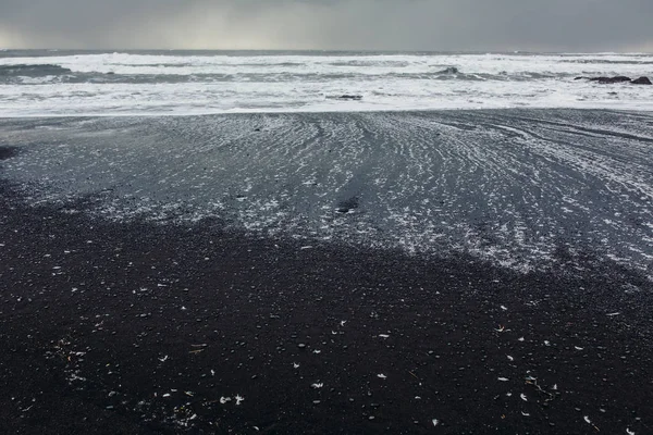 Seashore with black sand and stones — Stock Photo, Image