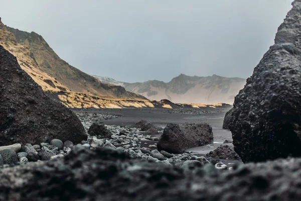 Mar com areia preta e pedras — Fotografia de Stock