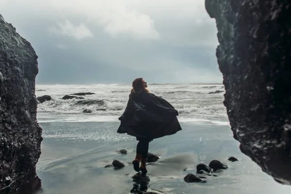 Mulher em pé na praia com areia preta — Fotografia de Stock