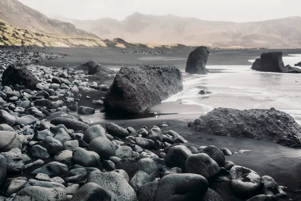 Море с черным песком и камнями — стоковое фото